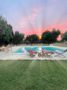 a pool with chairs and a rainbow in the sky at Masseria I Raffi b&b in Monopoli