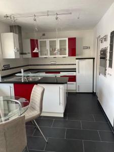 a kitchen with red and white cabinets and a glass table at Maisonette Apartment Family & Business nähe Heidelberg I Küche I 6 Schlafplätze in Sinsheim