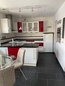 une cuisine avec des placards rouges et blancs et une table en verre dans l'établissement Maisonette Apartment Family & Business nähe Heidelberg I Küche I 6 Schlafplätze, à Sinsheim