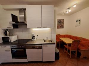 eine Küche mit weißen Schränken und einem Tisch mit einem Esszimmer in der Unterkunft Appartement Haus Gatterer in Obertilliach