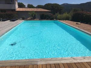 duży niebieski basen z drewnianym tarasem w obiekcie Mini villa proche des plus belles plages w mieście Porto-Vecchio