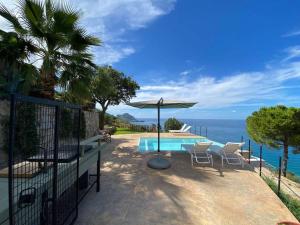a patio with a table and an umbrella and the ocean at Cefalu - luxury seaview villa x10 in Cefalù