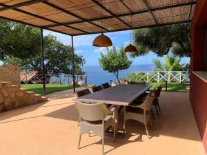 una mesa y sillas en un patio con vistas al océano en Cefalu - luxury seaview villa x10, en Cefalú