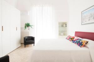 a bedroom with a white bed and a black chair at Casa Fernanda in Monopoli