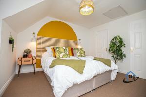 a bedroom with a large bed with a yellow headboard at Ironside House, king or twin beds, free parking, workspace, free wi-fi, corporates, pets, sleeps 8 in Thrapston