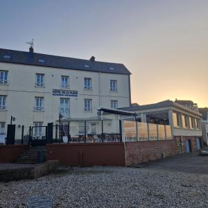 a large white building with a patio in front of it at Hotel De La Plage in Quiberville