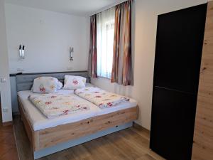 um quarto com uma cama com duas almofadas e uma janela em Appartement Haus Gatterer em Obertilliach