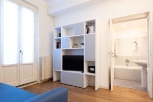 a bathroom with a tv in a white room at Porta Venezia Elegant Penthouse with Terrace in Milan