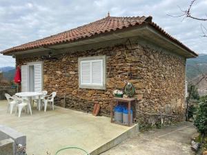 a stone house with a table and chairs in front of it at Casa Paraíso in Ribeira de Pena +7 photos
