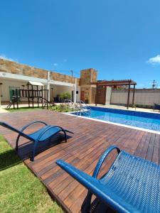 una terraza con 2 sillas azules junto a una piscina en House Aconchegante Ponta Negra en Natal