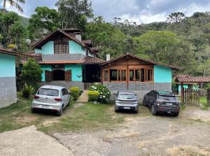 two cars parked in front of a house at Pousada Brilho da Natureza in Visconde De Maua