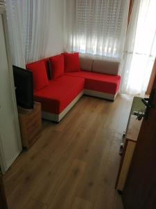 un soggiorno con divano rosso e TV di Apartmani ,studija i sobe Savić a Soko Banja