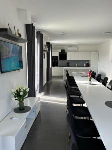 a dining room with a long white table and black chairs at Laura Apartmanház in Mórahalom
