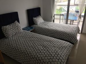 a bedroom with two beds and a chair and a window at Grand Apartement a Blanca Beach Sidi Rehal in Sidi Rahal