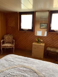 a bedroom with a bed and a chair and windows at Maison de vacances 