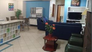 uma sala de estar com um sofá azul e uma mesa com flores em Hotel Arthur Shambala em Encarnación