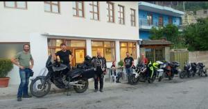 een groep mannen die voor een gebouw met motorfietsen staan bij Hotel Bebej Tradicional in Gjirokastër