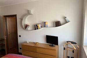 a bedroom with a desk with a television and books on the wall at FIERA MILANO-RHO APARTMENT in Pero