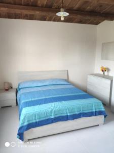 - une chambre blanche avec un lit bleu et deux commodes dans l'établissement Casa vacanze La Meridiana, à Donnalucata