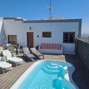 a swimming pool with chairs and a couch on a patio at Casona La Orilla 1908 Tías in Tías
