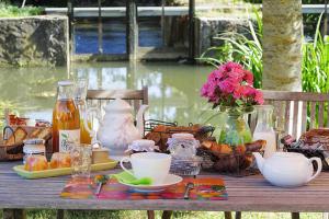 un tavolo da picnic con cibo, bevande e fiori di Chambres d'Hôtes Au Moulin 