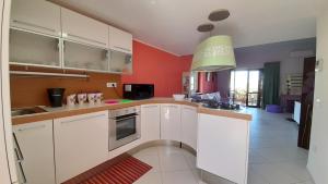 uma cozinha com armários brancos e paredes vermelhas em Il Sogno Loft Indipendente em Crotone