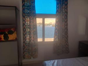 Schlafzimmer mit einem Fenster mit Blick auf das Wasser in der Unterkunft Kafana Guest House Nile View in Assuan