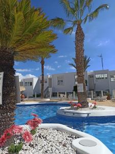 a swimming pool with palm trees in front of a building at AZAHARA PLAYA LAS VISTAS - STUDIO - Playa de Las Americas in Playa de las Americas