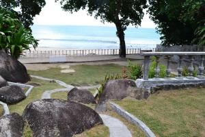 a garden with rocks and a bench and the beach at Riva D Etruschi Seychelles in Bel Ombre