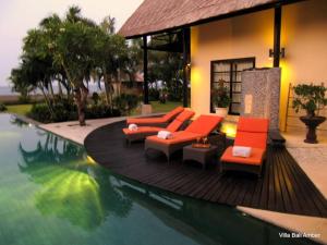a swimming pool with orange furniture and a house at Bali Amber Villa in Banjar