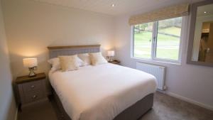 a bedroom with a large white bed with a window at Llyn Padarn Lodge in Betws-y-coed
