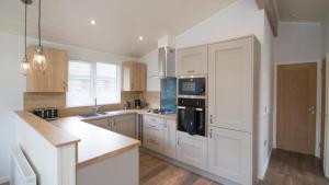 a kitchen with white cabinets and a counter top at Llyn Padarn Lodge in Betws-y-coed