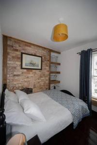 1 dormitorio con cama blanca y pared de ladrillo en Sunmount, en Youghal