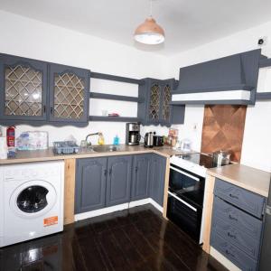 a kitchen with blue cabinets and a white dishwasher at Views of Youghal Bay in Youghal