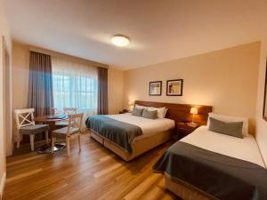 バリナスローにあるMoycarn Lodge & Marinaのベッド2台、テーブルと椅子が備わるホテルルームです。
