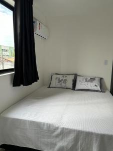 uma cama branca num quarto com uma janela em Apartamento Intermares em Cabedelo