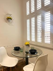 a dining room with a glass table and white chairs at Cosmopolitan Stays in London