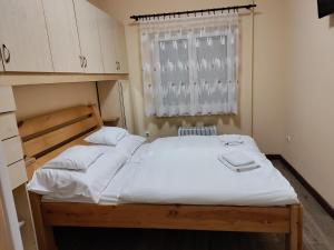 sypialnia z dużym białym łóżkiem i oknem w obiekcie Damjanich apartman w mieście Kaposvár