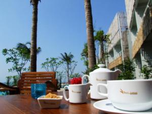 a table with cups and bowls of food on it at Bari Lamai Resort in Ban Phe