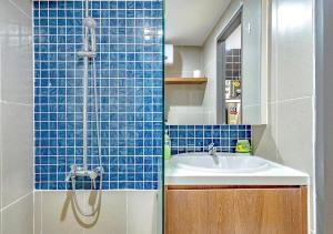 W łazience znajduje się umywalka i prysznic z niebieskimi kafelkami. w obiekcie The Peony Apartment w Ho Chi Minh