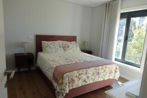 a bedroom with a bed with a floral bedspread and a window at Montinho 313 in Arouca