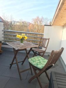 uma mesa e cadeiras numa varanda com um vaso de flores em Dachgeschosszimmer mit Terrasse em Wismar