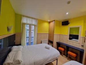 a bedroom with yellow walls and a bed and a desk at Pension Izar Bat Guesthouse in San Sebastián