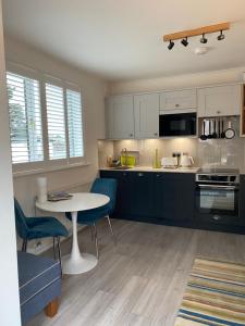 a kitchen with a table and blue chairs and a table at Little Trevio - seaside haven with parking and sea views in Brixham