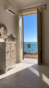 an open door to a balcony with a view of the ocean at Magellano Suite. Fronte Mare + Free Park + Wi-Fi in Porto Empedocle