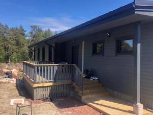 a black house with a porch and a deck at Kemping in Föglö