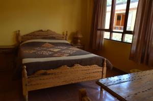 1 dormitorio con cama de madera y ventana en Hostal Coronel Pedro Arraya, en Tupiza