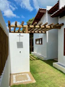 a white house with a wooden pergola at Casa Surya in São Miguel do Gostoso