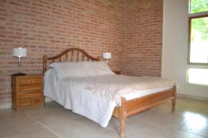 a bedroom with a bed and a brick wall at Coqueto departamento, Jardines del Rey in Neuquén