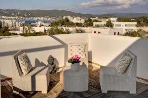 un balcón con 2 sillas y un jarrón con flores en Can Agua IBIZA - Fantastic Villa with pool & BBQ, en Sant Josep de sa Talaia